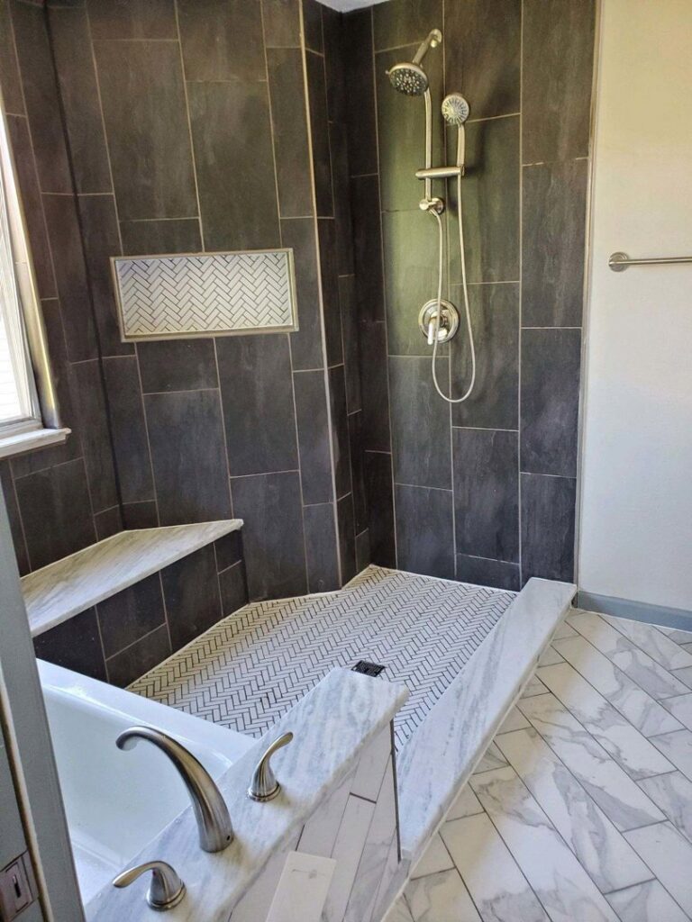 A newly tiled shower with a built-in bench and modern fixtures, completed by Infinite Creations Construction, LLC in Denver, CO