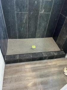 A newly tiled shower floor and lower walls with black tiles and a metallic mosaic by HMI Contractors in Cincinnati, OH.