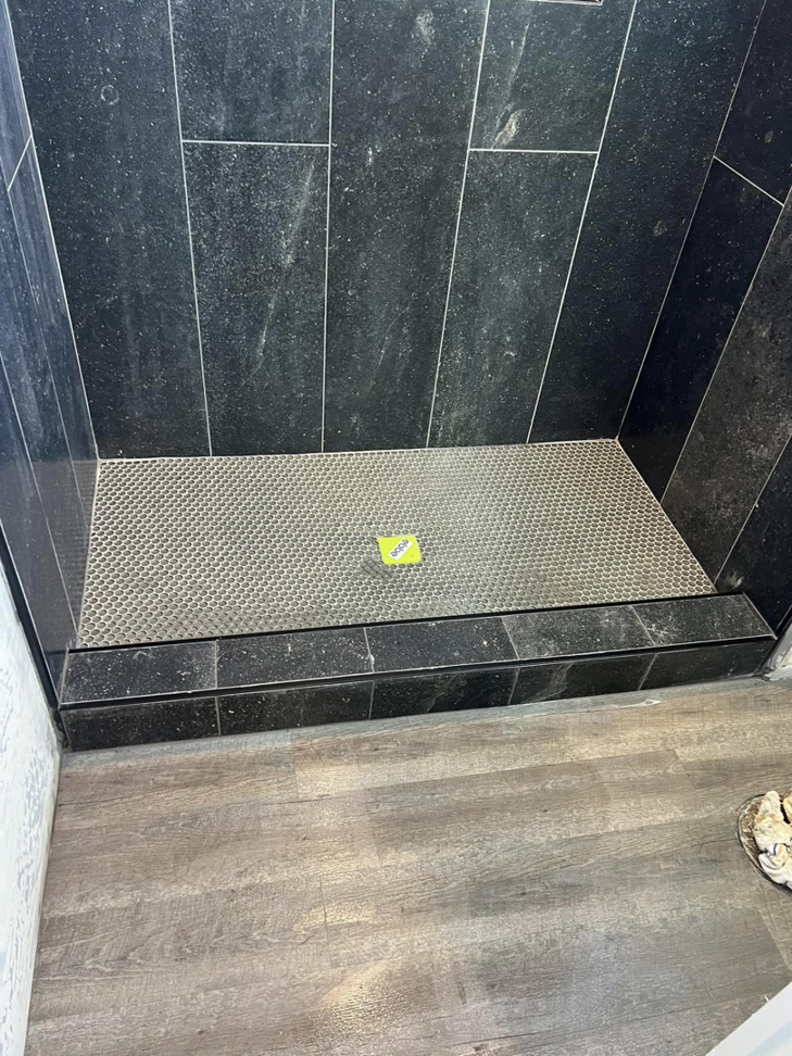 A newly tiled shower floor and lower walls with black tiles and a metallic mosaic by HMI Contractors in Cincinnati, OH.