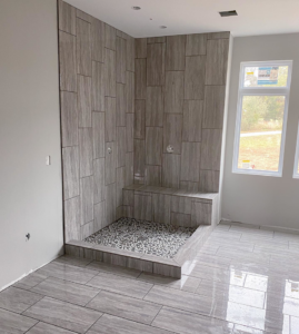 Newly completed tiled shower installation with pebble floor by Clean Cut Tile LLC in St. Louis, MO.
