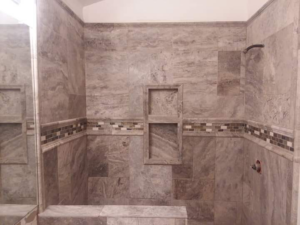 A newly tiled shower with a built-in niche and bench, installed by Brauny Home Services, LLC in Arvada, CO