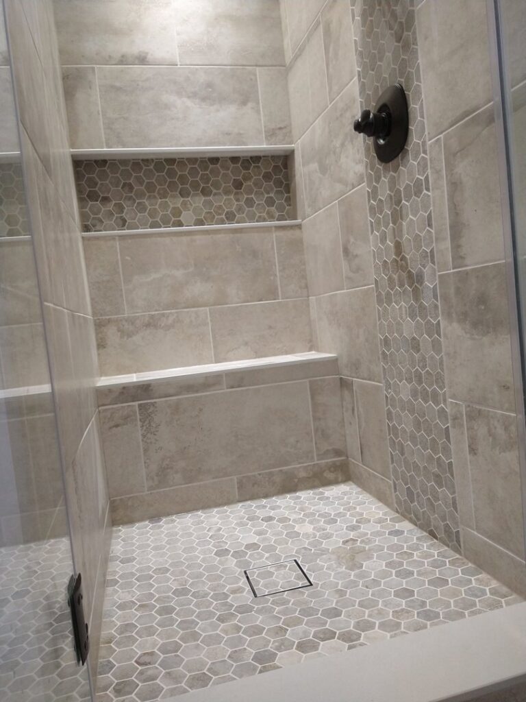 A newly tiled shower with elegant hexagonal floor tiles and a convenient built-in niche, installed by Blas Home Remodeling LLC in New Castle, DE.