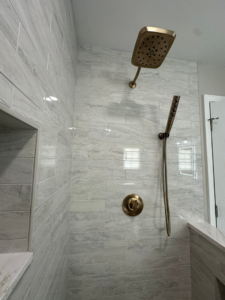 A newly tiled shower with a modern rain shower head and handheld sprayer by Quality Work Home Services in Syracuse, NY.