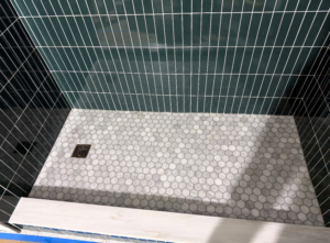 A newly tiled shower stall with dark green subway and hexagonal floor tiles by All In Service Group, LLC in Chicago, IL.