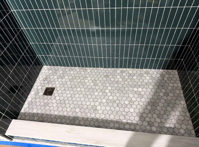 A newly tiled shower stall with dark green subway and hexagonal floor tiles by All In Service Group, LLC in Chicago, IL.