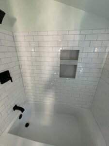 A newly tiled shower and tub area with white subway tiles and a built-in niche by 3Rivers General Contracting in Pittsburgh, PA.