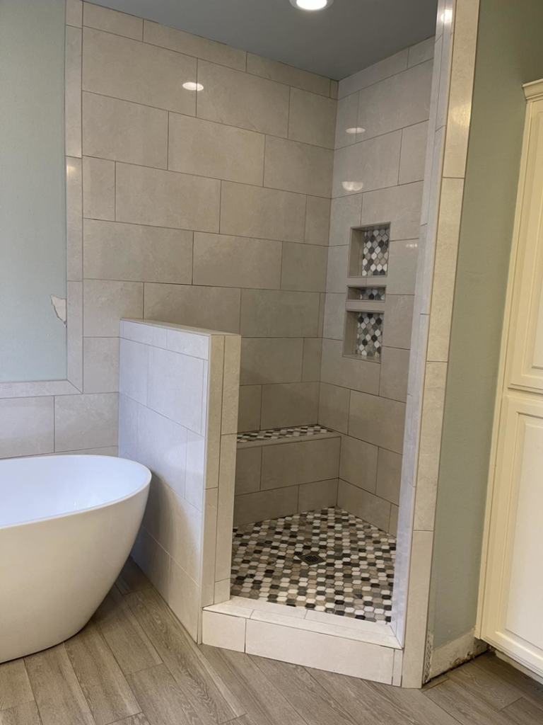 Newly tiled walk-in shower with a built-in bench and decorative niche by B&W Designer Tile in Tulsa, OK