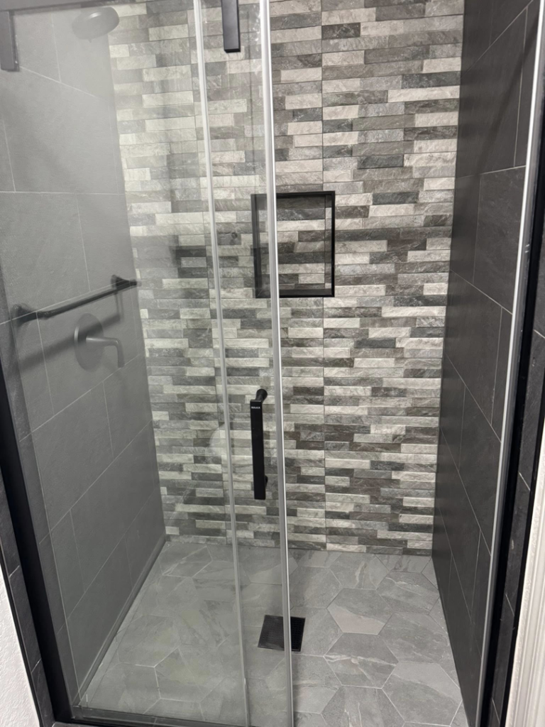 Newly tiled walk-in shower with glass door installed by Castillo Contracting & Remodeling in Broken Arrow, OK.