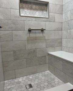 A newly tiled walk-in shower with a built-in bench, niche, and grab bar, completed by TileWorks in Birmingham, AL.