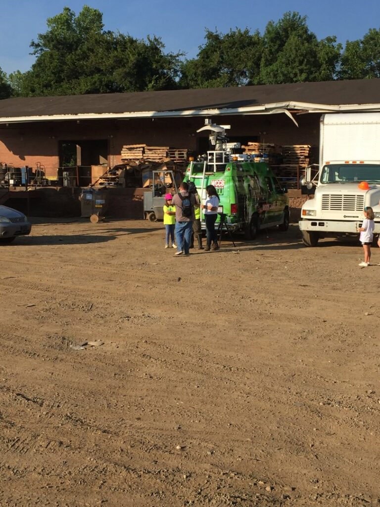 A news van and people gathered at the Queen City Metal Recycling & Salvage facility in Charlotte, NC.