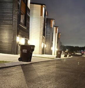 J.E. McMurtry Disposal & Recycling trash bins lined up on a residential street at night in Nashville, TN.
