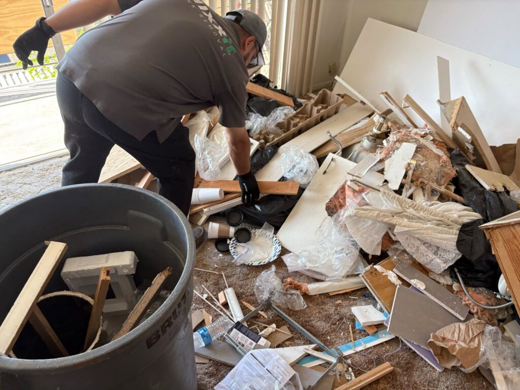 A Nixxit Junk Removal employee sorting through a large pile of construction debris and general junk in Castro Valley, CA.