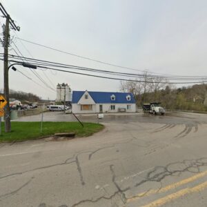 The Northeast-Paving business location with a blue-roofed building and asphalt plant in the background in Bangor, ME