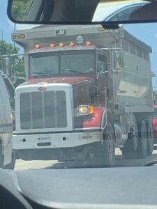 A large dump truck with the Northeast-Paving logo on the front, ready for construction projects in Bangor, ME