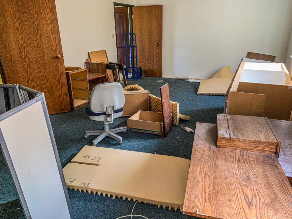 A room filled with disassembled office furniture and debris, ready for removal by Junk Junkees in Peoria, AZ.