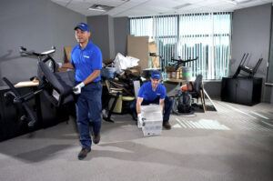 Two 1-800-GOT-JUNK? employees removing office chairs and boxes during a commercial junk removal in Bronx, NY
