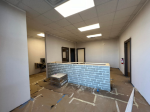 An interior office renovation project showing a partially built reception desk with brick veneer by Southern Plastering in Memphis, TN.
