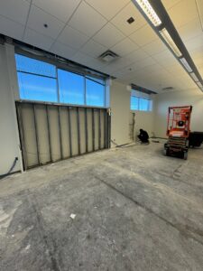 Office space with a wall partially removed, showing demolition work and debris for junk removal by HAVOC Demolition in Scottsdale, AZ.
