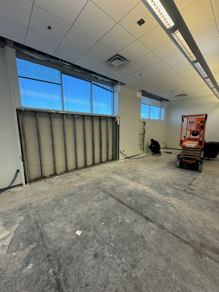 Office space with a wall partially removed, showing demolition work and debris for junk removal by HAVOC Demolition in Scottsdale, AZ.