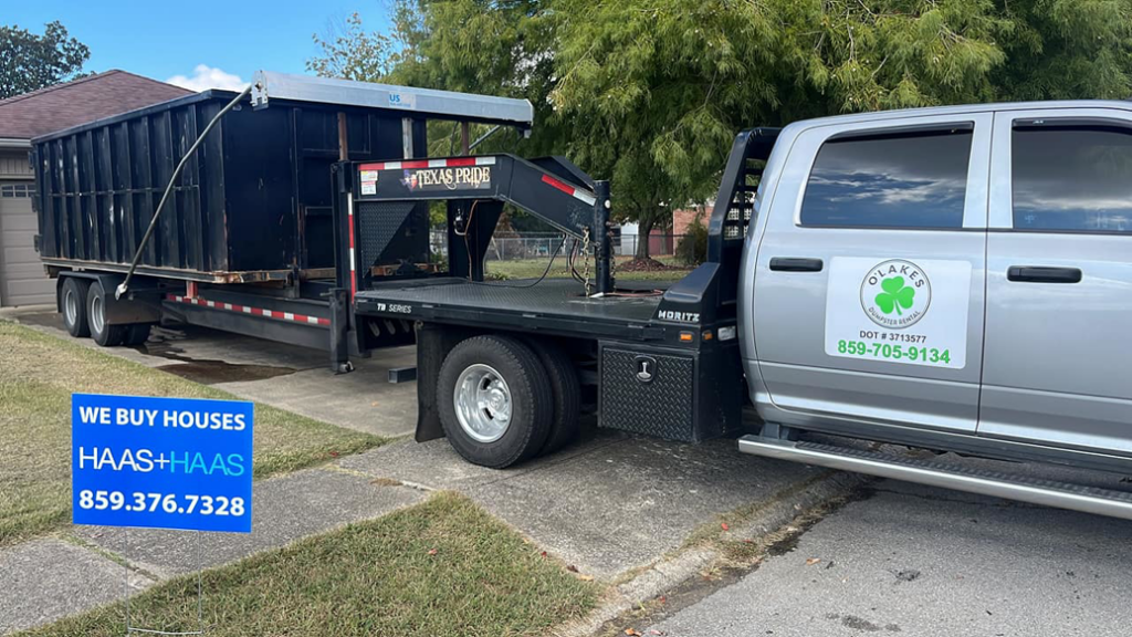 An O'Lakes Dumpster Rental truck hauling a full roll-off dumpster on a trailer in Lexington, KY.