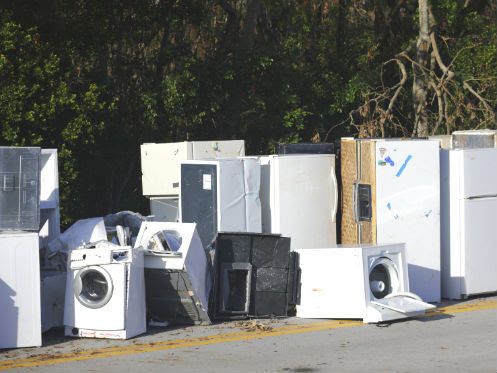 A collection of old refrigerators, washing machines, and other appliances piled by the roadside, ready for pickup by Trashouts Junk Removal in Pembroke Pines, FL.