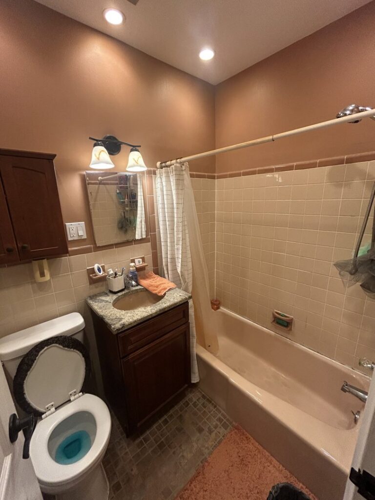An old bathroom with a pink bathtub and dated tiles, awaiting renovation by MPH Design in Philadelphia, PA.
