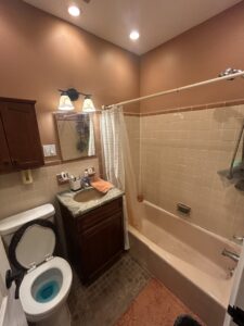 An old bathroom with a pink bathtub and dated tiles, awaiting renovation by MPH Design in Philadelphia, PA.