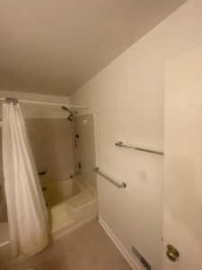 An old bathroom with a tub and shower combo, showing wear before a remodel by Done Right Construction in Johnston, IA.