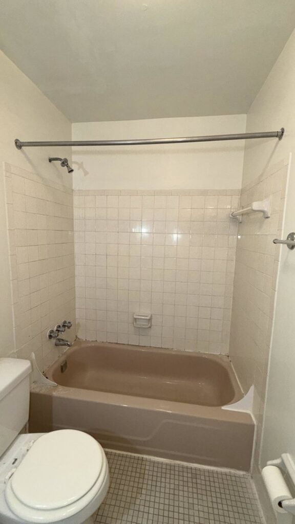 An old, worn brown bathtub and tiled walls before refinishing by Phillys Finest Tub & Tile Refinishing in Philadelphia, PA