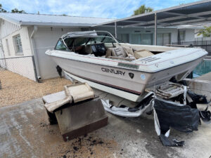 An old boat and surrounding debris being removed from a residential property by AAA Rousse Junk Removal Services Inc of Florida in Tampa, FL.