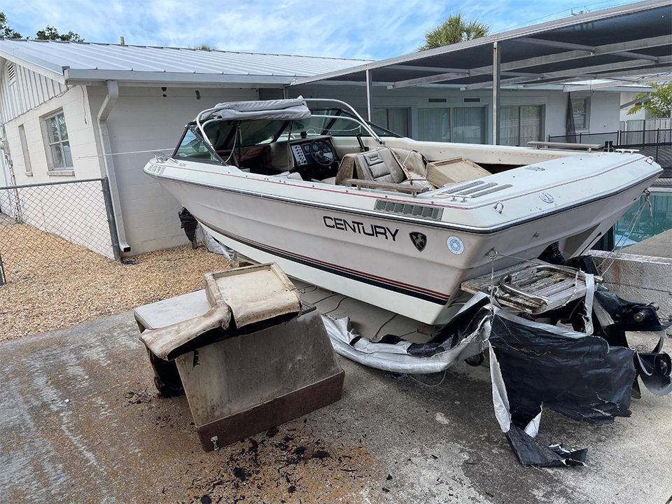 An old boat and surrounding debris being removed from a residential property by AAA Rousse Junk Removal Services Inc of Florida in Tampa, FL.