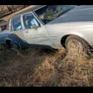 An old, damaged car sitting in a field, representing scrap metal removal services by 701 Scrap in Williston, ND.