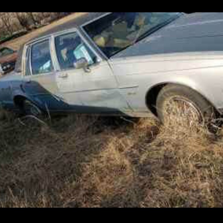 An old, damaged car sitting in a field, representing scrap metal removal services by 701 Scrap in Williston, ND.