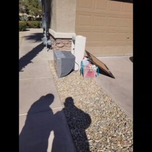 Old electronics and appliances, including a TV and AC unit, placed for junk removal at a home in Las Vegas, NV