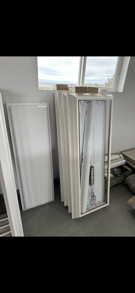 Old fluorescent light fixtures and panels piled up for junk removal by Haul My Load LLC in Caldwell, ID.