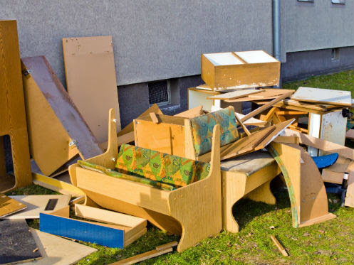 A large pile of old wooden furniture and various debris stacked outdoors, indicating a junk removal job by Trashouts Junk Removal in Pembroke Pines, FL.