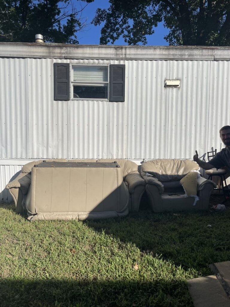 Old furniture, including a couch and chair, placed outside a mobile home for junk removal by Little Tykes Property Preservation in Independence, MO.