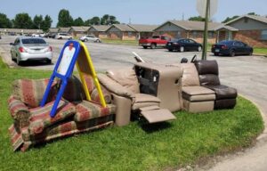 A pile of old couches and recliners on a grassy area, ready for junk removal by Urban Junk Removal, LLC in Springdale, AR.
