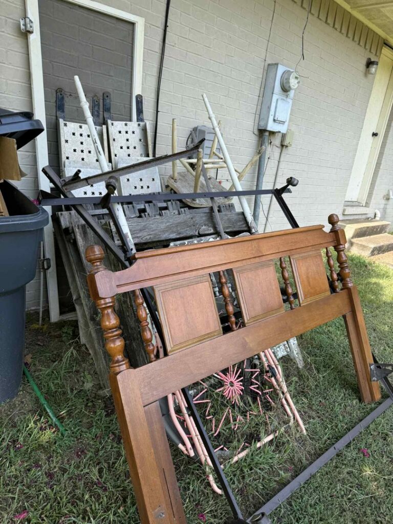 A pile of old furniture, including a wooden headboard and chairs, ready for removal by Junk Hawgs Removal and Rentals in Russellville, AR.