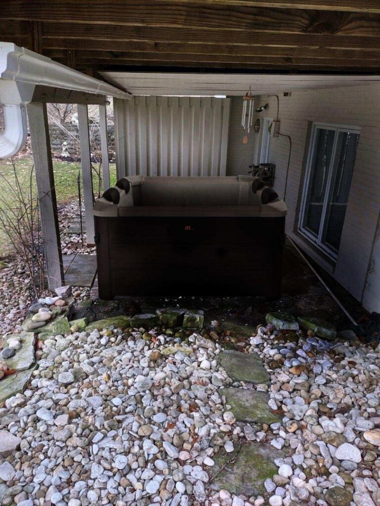 An old hot tub sitting on a rocky patio under a deck, ready for removal by 1-800-Declutter in Cincinnati, OH.