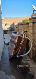 An old, rusty hot tub in a narrow side yard, ready for removal by New Haul Junk Removal in Los Angeles, CA.