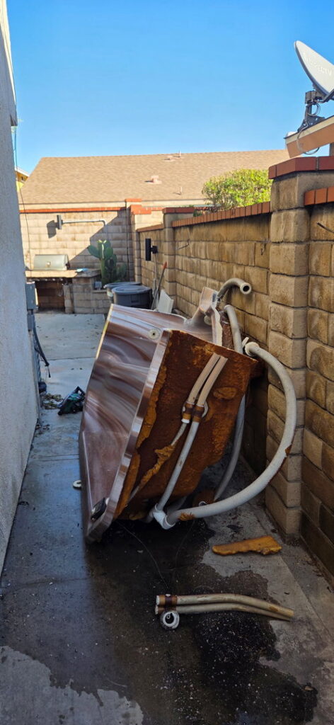 An old, rusty hot tub in a narrow side yard, ready for removal by New Haul Junk Removal in Los Angeles, CA.