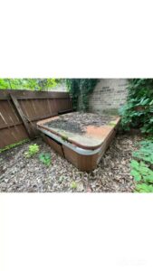 An old, dirty hot tub in a backyard awaiting removal by Strong Lion Junk Removal in Fayetteville, AR.
