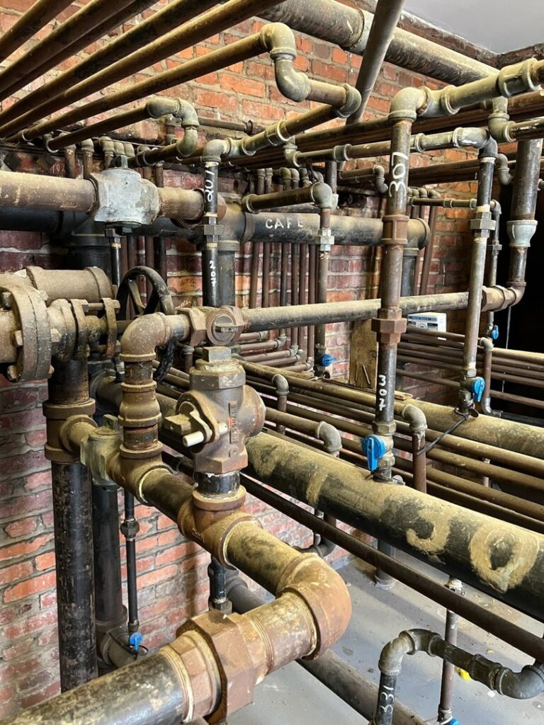 A dense network of old industrial plumbing pipes, showcasing the type of systems JF Plumbing & Heating services in Rockville, MD.