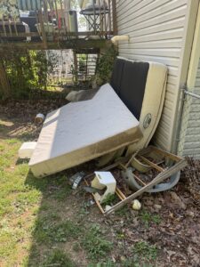 An old mattress, box spring, and other items leaning against a house, ready for junk removal by Quick Lift Junk Removal in Hagerstown, MD.