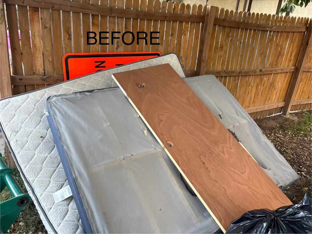 Old mattresses and a wooden board leaning against a fence before a junk removal service by Tiny Monster Junk Removal LLC in Denver, CO.