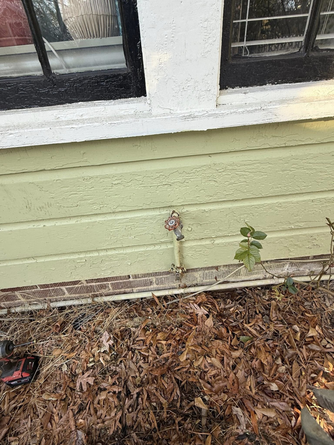 An older outdoor faucet on the exterior wall of a house, indicating potential repair or replacement services by Helms Plumbing and Drains in Charlotte, NC.