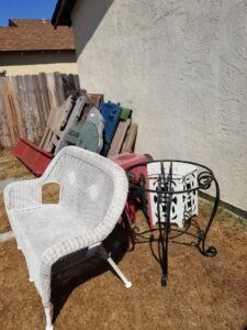 Pile of old patio furniture and various junk items in a yard awaiting removal by Johan's Junk Removal and Hauling in San Diego, CA