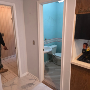 An older powder room with blue wallpaper and a pedestal sink, showing a space ready for renovation by Noble Home Improvements in Edison, NJ.