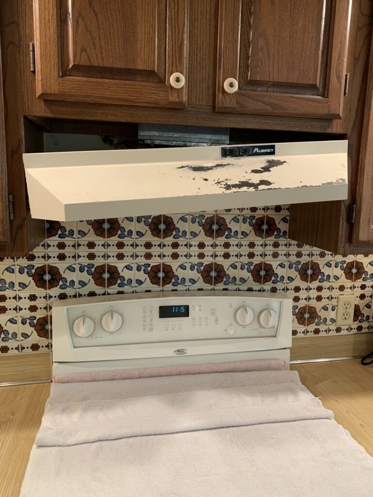 An old, damaged range hood being removed or replaced above a kitchen stove, a service provided by Folmar's Handyman & Remodeling in Lincoln, NE.